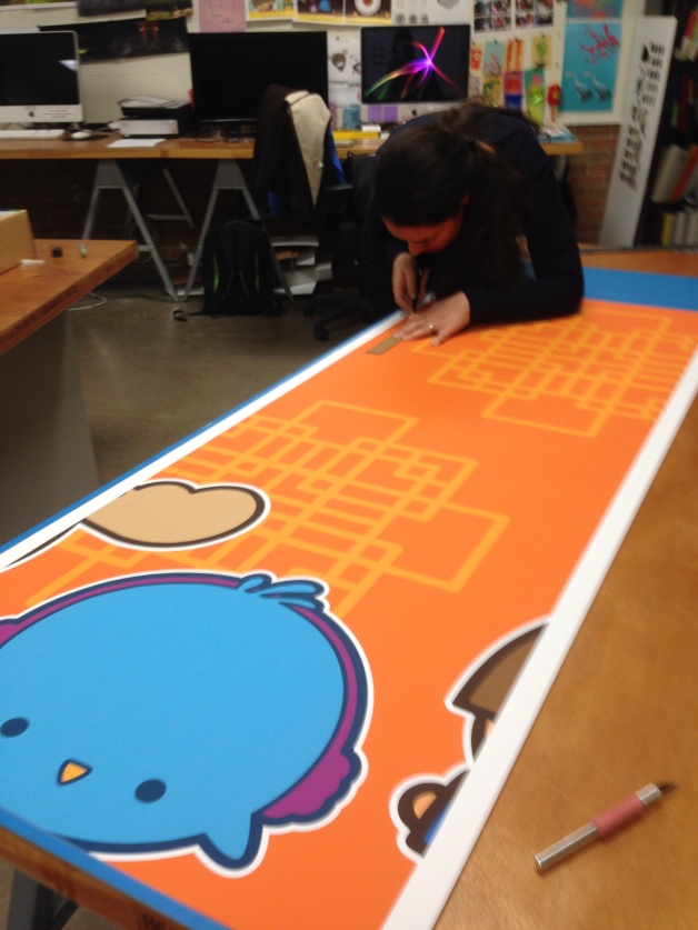 part of a poster series to be placed on the wall; my colleague Maryam helping to trim the posters to edge